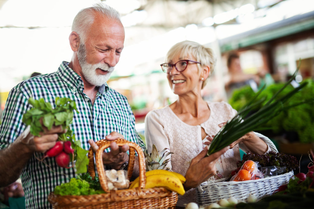 Happy senior couple buying fresh food at the market